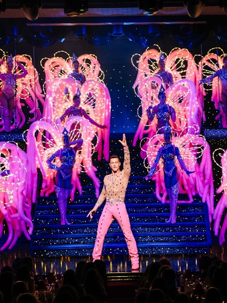 Performers on stage at the Moulin Rouge Show in Paris with vibrant costumes and lights.