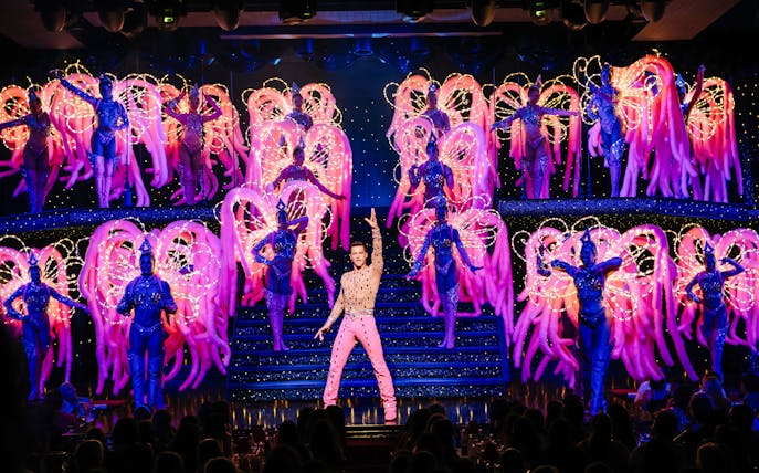 Performers on stage at the Moulin Rouge Show in Paris with vibrant costumes and lights.