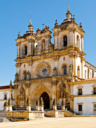 Alcobaça Monastery facade with twin bell towers and ornate rose window.