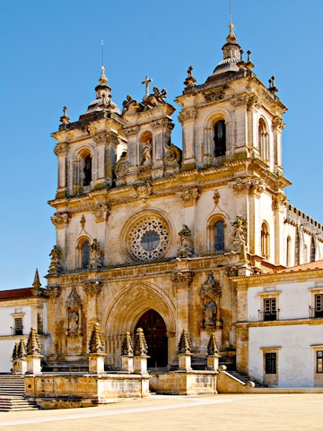 Alcobaça Monastery facade with twin bell towers and ornate rose window.