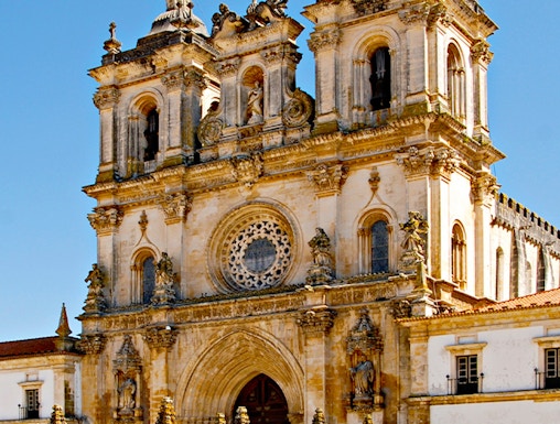 Alcobaça Monastery facade with twin bell towers and ornate rose window.