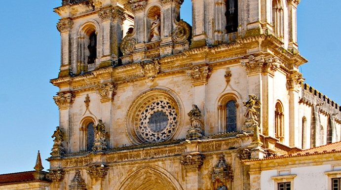 Alcobaça Monastery facade with twin bell towers and ornate rose window.