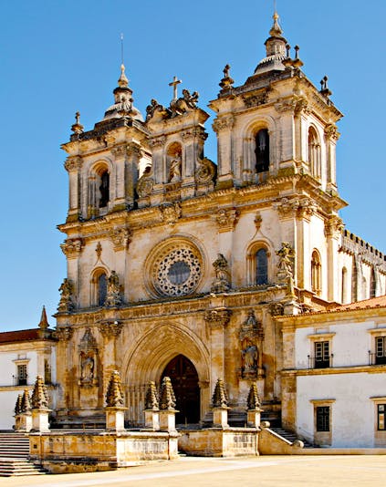 Alcobaça Monastery facade with twin bell towers and ornate rose window.
