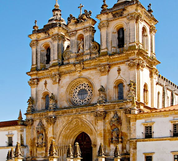 Alcobaça Monastery facade with twin bell towers and ornate rose window.
