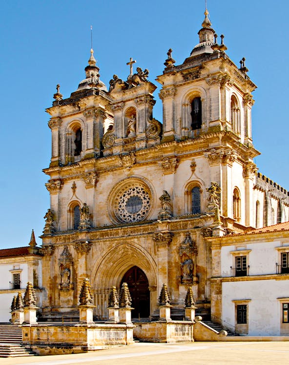 Alcobaça Monastery facade with twin bell towers and ornate rose window.