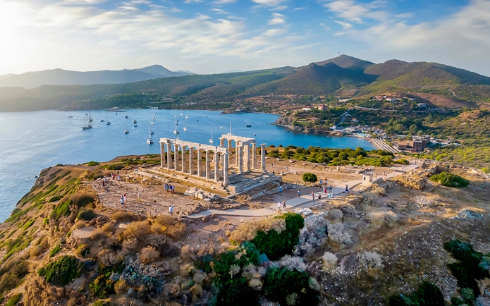 Temple of Poseidon at Cape Sounion overlooking the sea during sunset.