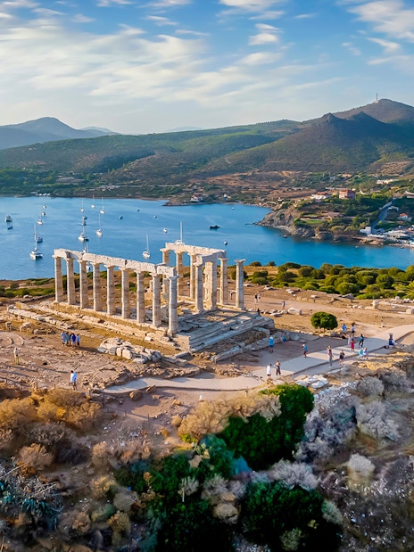 Temple of Poseidon at Cape Sounion overlooking the sea during sunset.