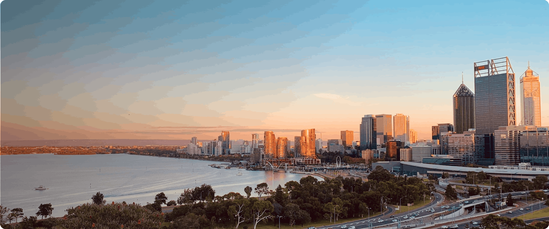 Perth city skyline at sunset with Swan River in the foreground.