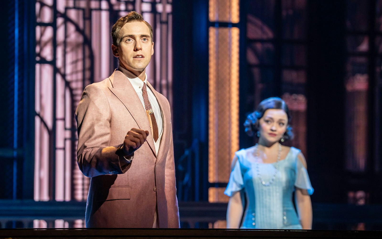 Actors performing The Great Gatsby Musical on stage with 1920s costumes and set design.