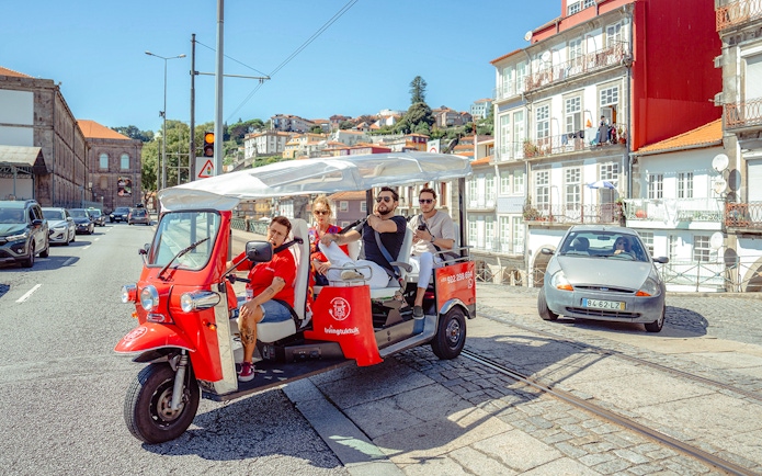 Porto city street with tourists on an electric tuk-tuk during a city tour.
