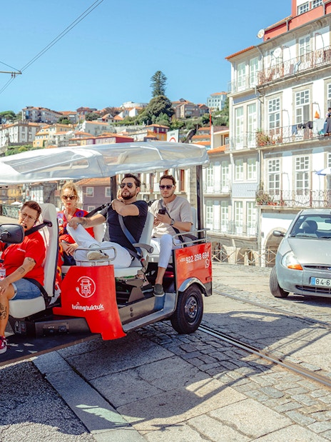 Porto city street with tourists on an electric tuk-tuk during a city tour.
