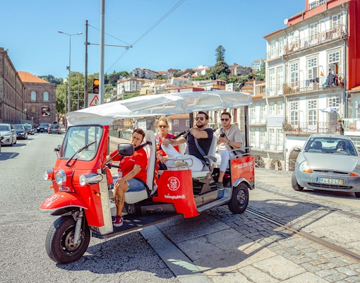 Porto city street with tourists on an electric tuk-tuk during a city tour.