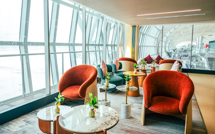 Coral Airport Lounge seating area at Suvarnabhumi Airport with modern chairs and tables.
