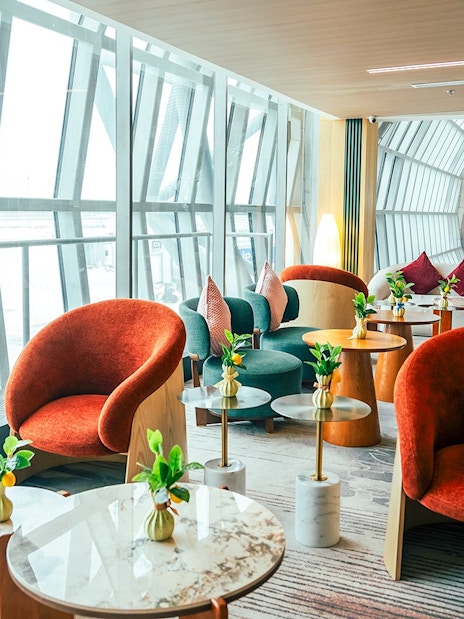 Coral Airport Lounge seating area at Suvarnabhumi Airport with modern chairs and tables.