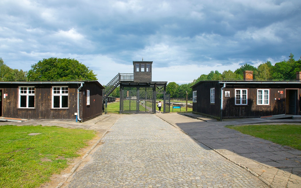 Stutthof Concentration Camp entrance with wooden buildings and watchtower.