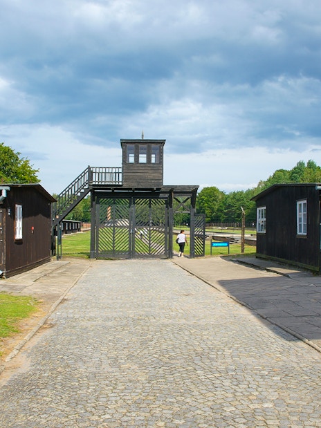 Stutthof Concentration Camp entrance with wooden buildings and watchtower.