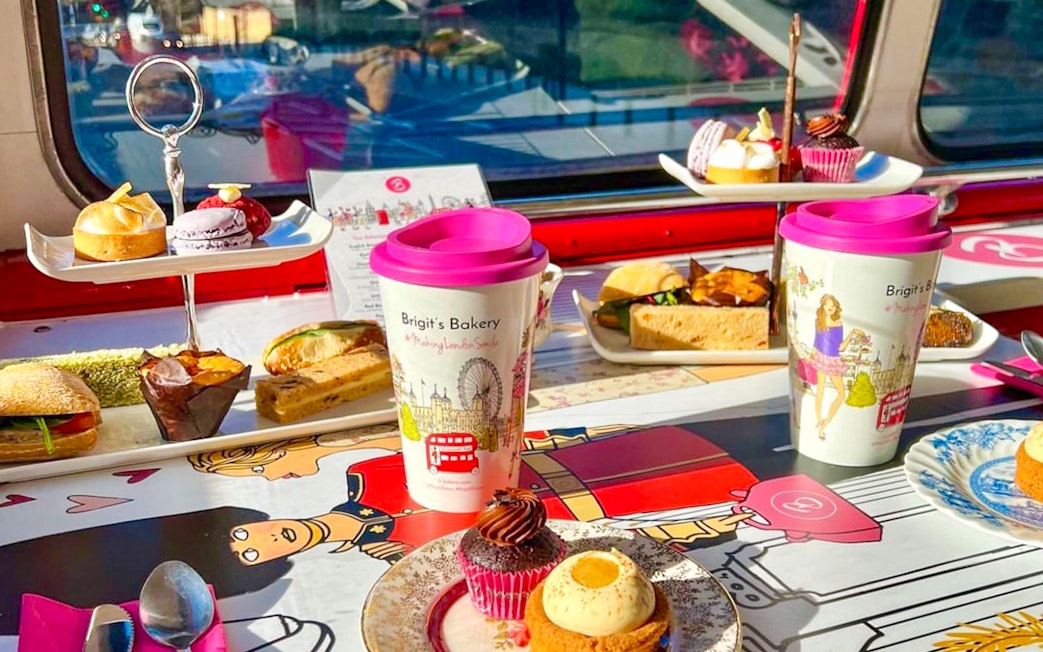 Afternoon tea setup with pastries and sandwiches on a London bus tour table.