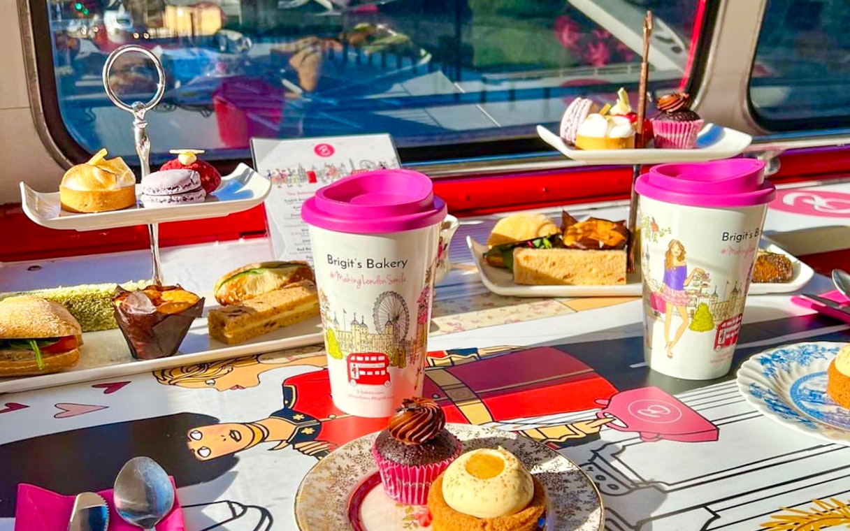 Afternoon tea setup with pastries and sandwiches on a London bus tour table.