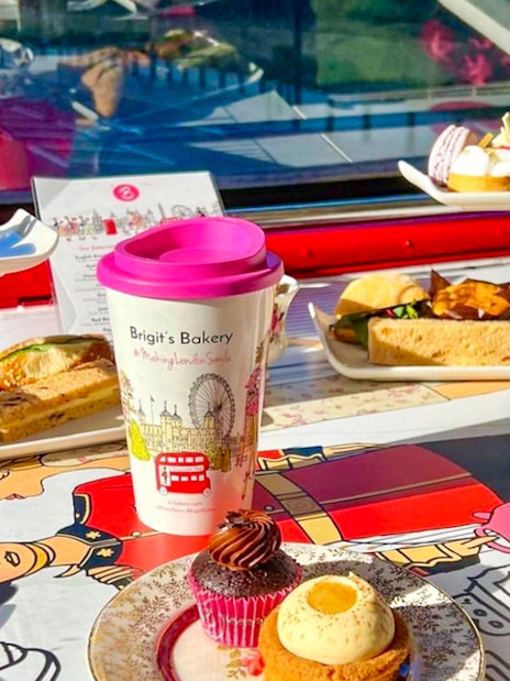 Afternoon tea setup with pastries and sandwiches on a London bus tour table.