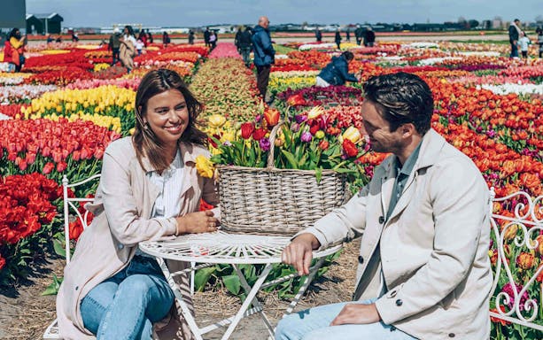 Couple sitting at a table surrounded by colorful tulip fields in Keukenhof.