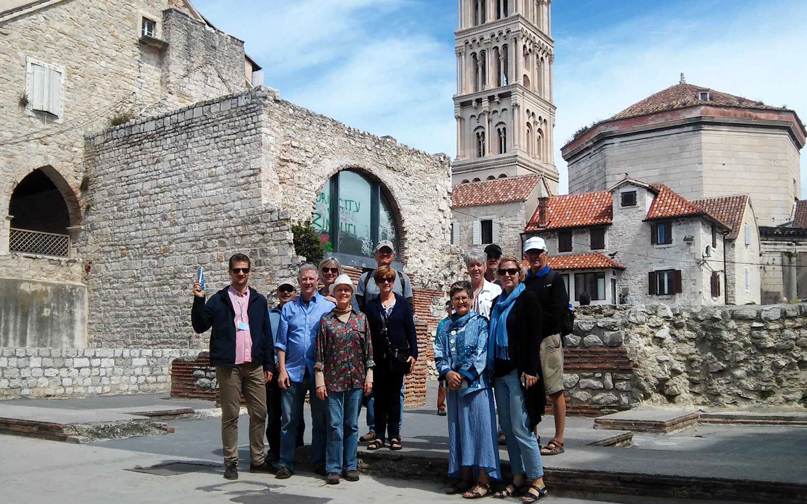 Group of tourists at Diocletian's Palace in Split, Croatia, with historic architecture in the background.