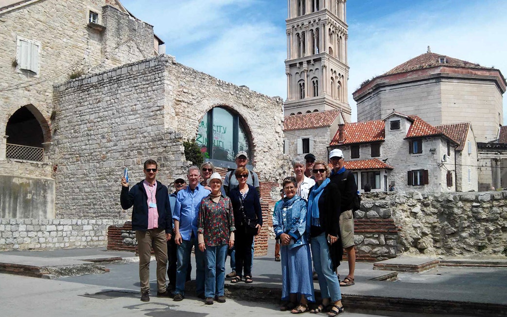 Group of tourists at Diocletian's Palace in Split, Croatia, with historic architecture in the background.