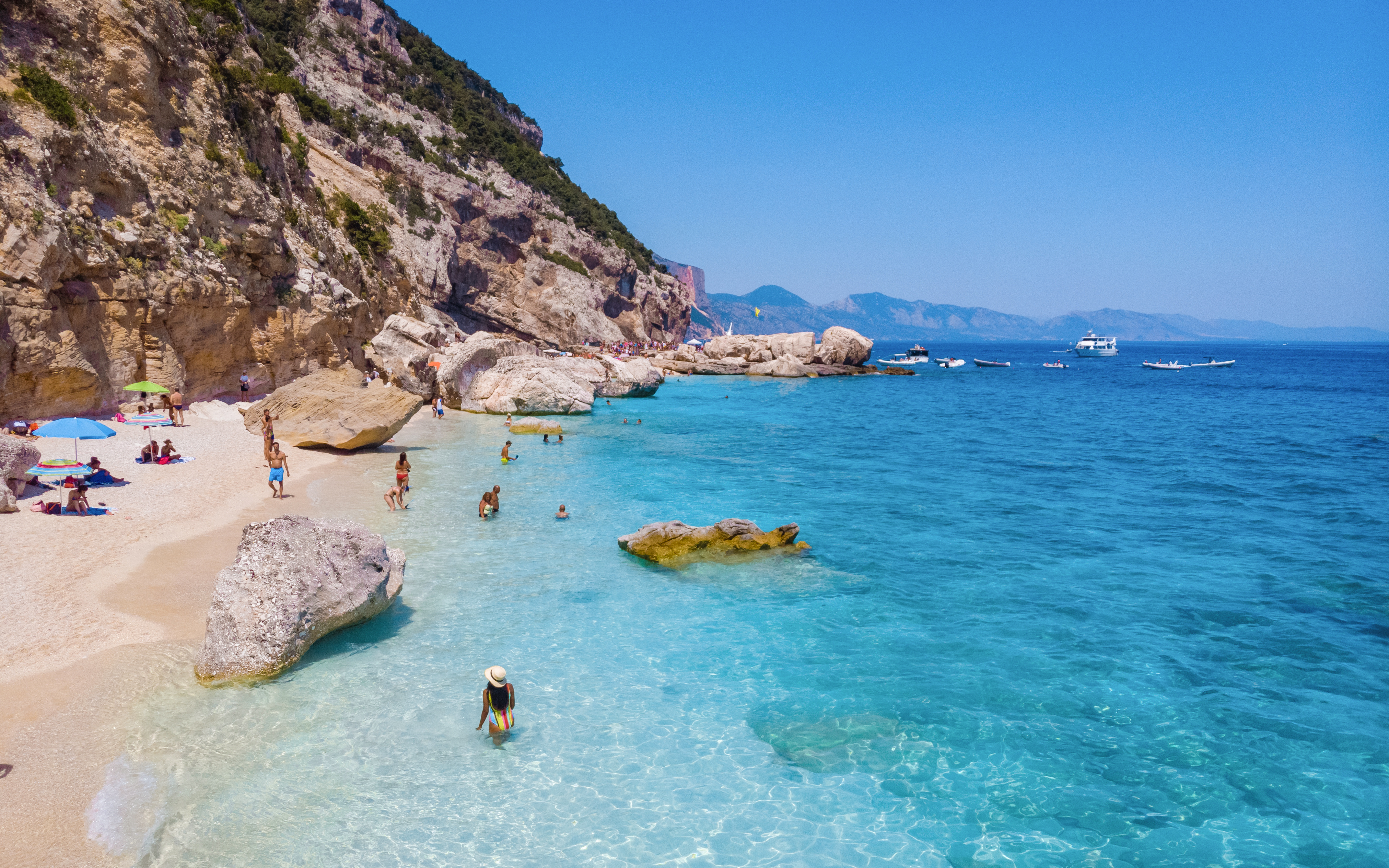 People enjoying the beach and clear waters in Gulf of Orosei, Sardinia, Italy.