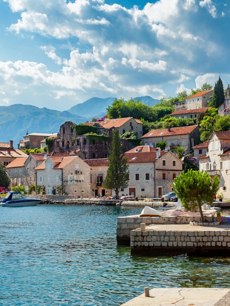 Perast town waterfront with historic stone buildings and mountains in Montenegro.