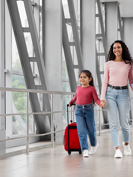 Family walking through airport terminal with luggage for a generic airport transfer.