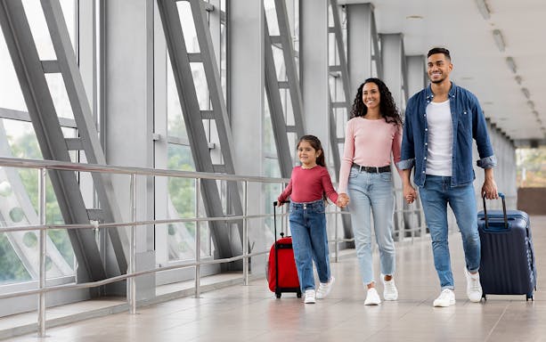 Family walking through airport terminal with luggage for a generic airport transfer.