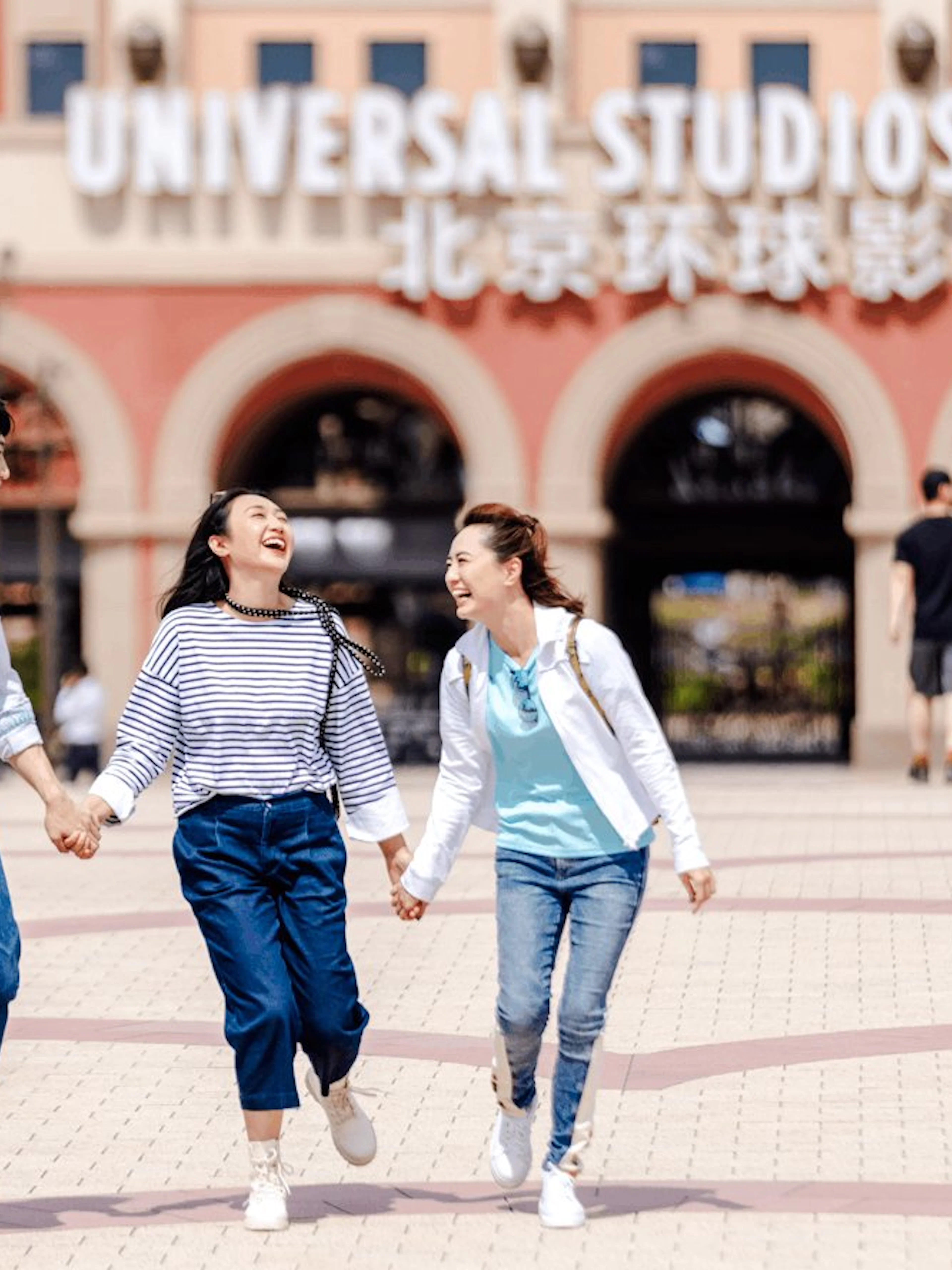 Visitors walking joyfully at Universal Studios Beijing entrance.