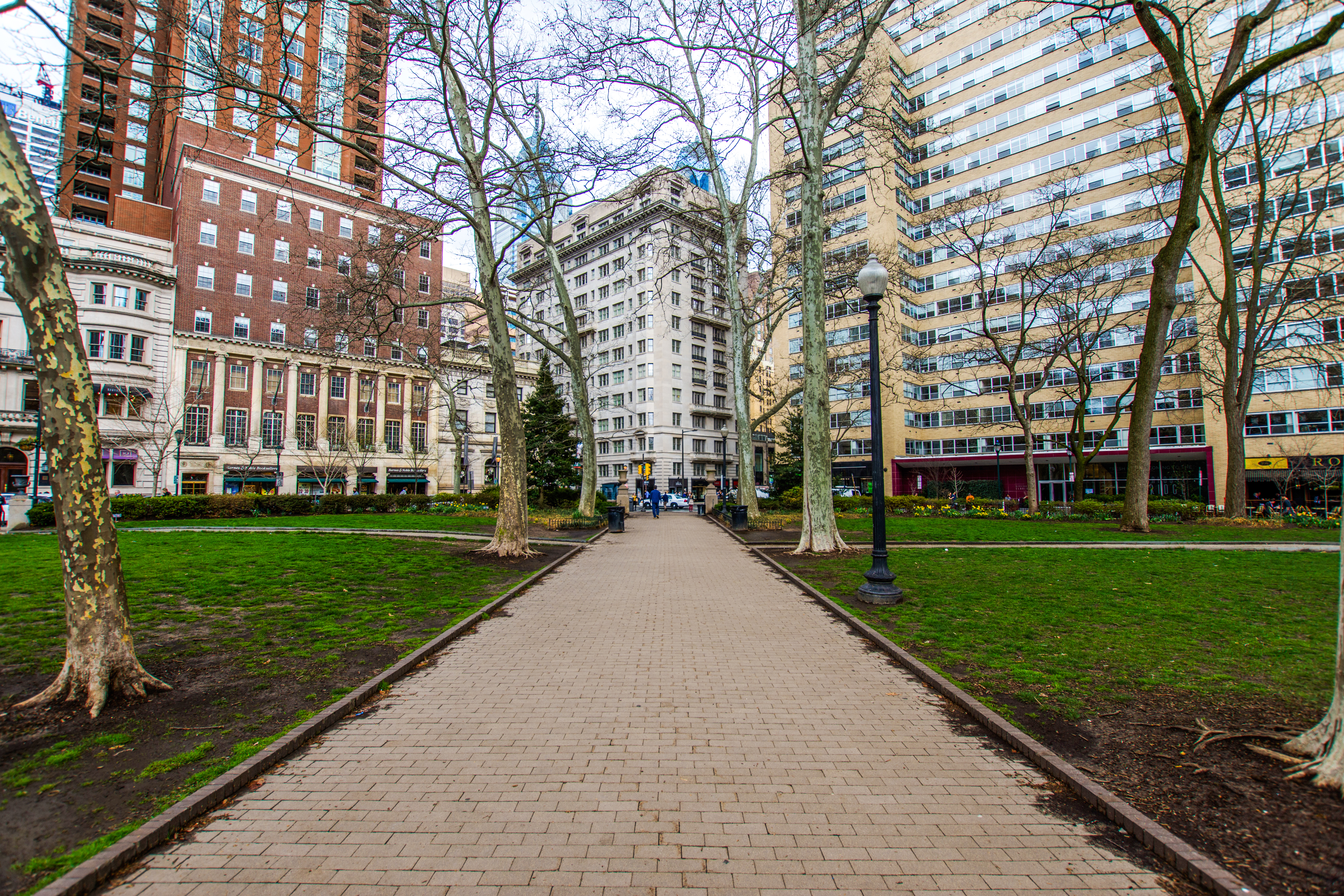 Pathway through Rittenhouse Square, Philadelphia, with surrounding buildings and trees.