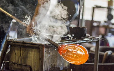 Glassblowing demonstration in Murano, Venice, with molten glass on a rod.