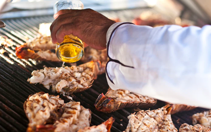 Grilling lobster tails on a barbecue during a sunset cruise in Cancun.