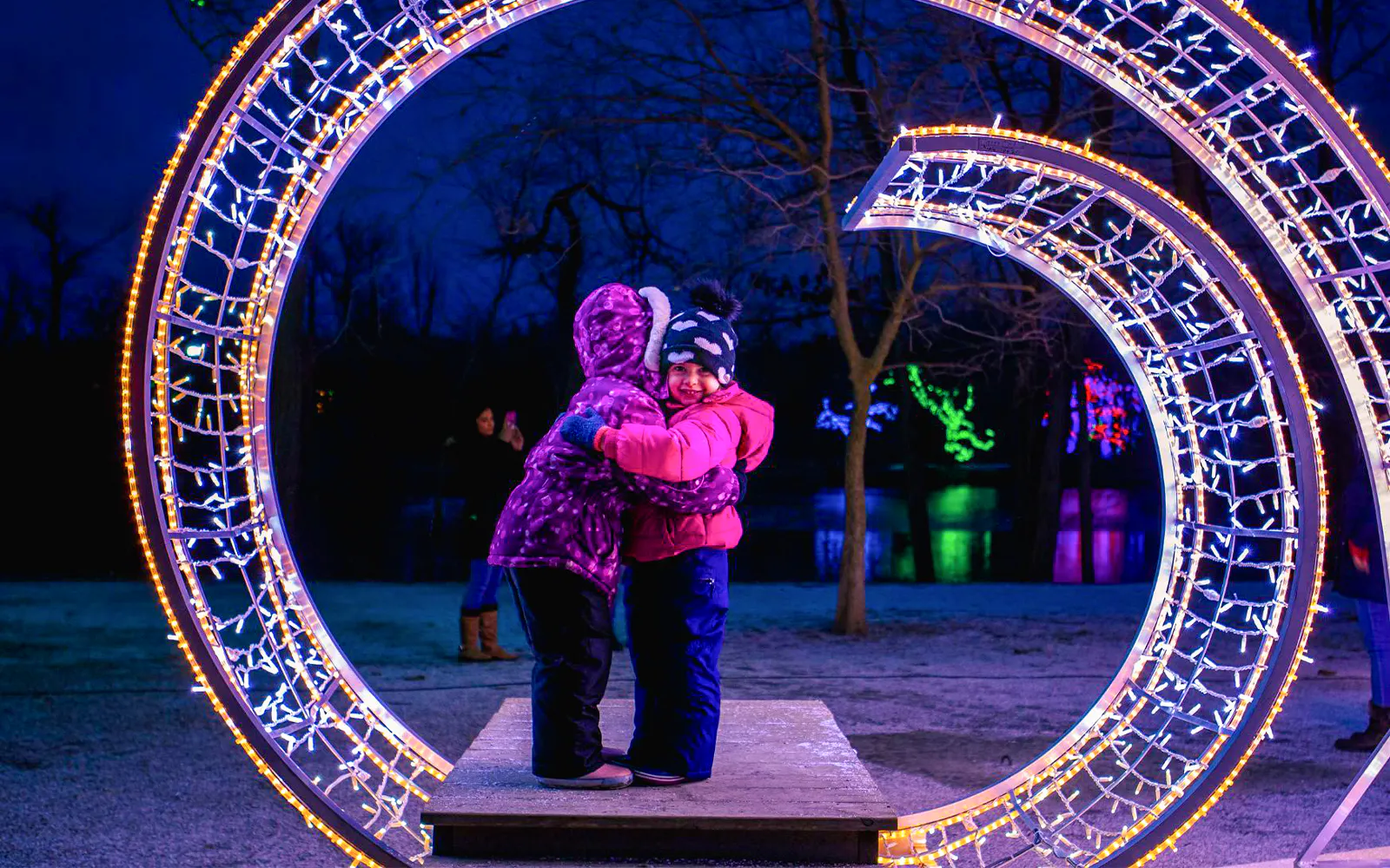 Children embracing under illuminated arch at Niagara Festival of Lights Tour.