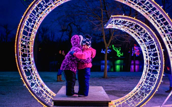 Children embracing under illuminated arch at Niagara Festival of Lights Tour.