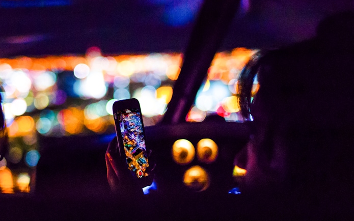 Person photographing city lights from helicopter cockpit at night.