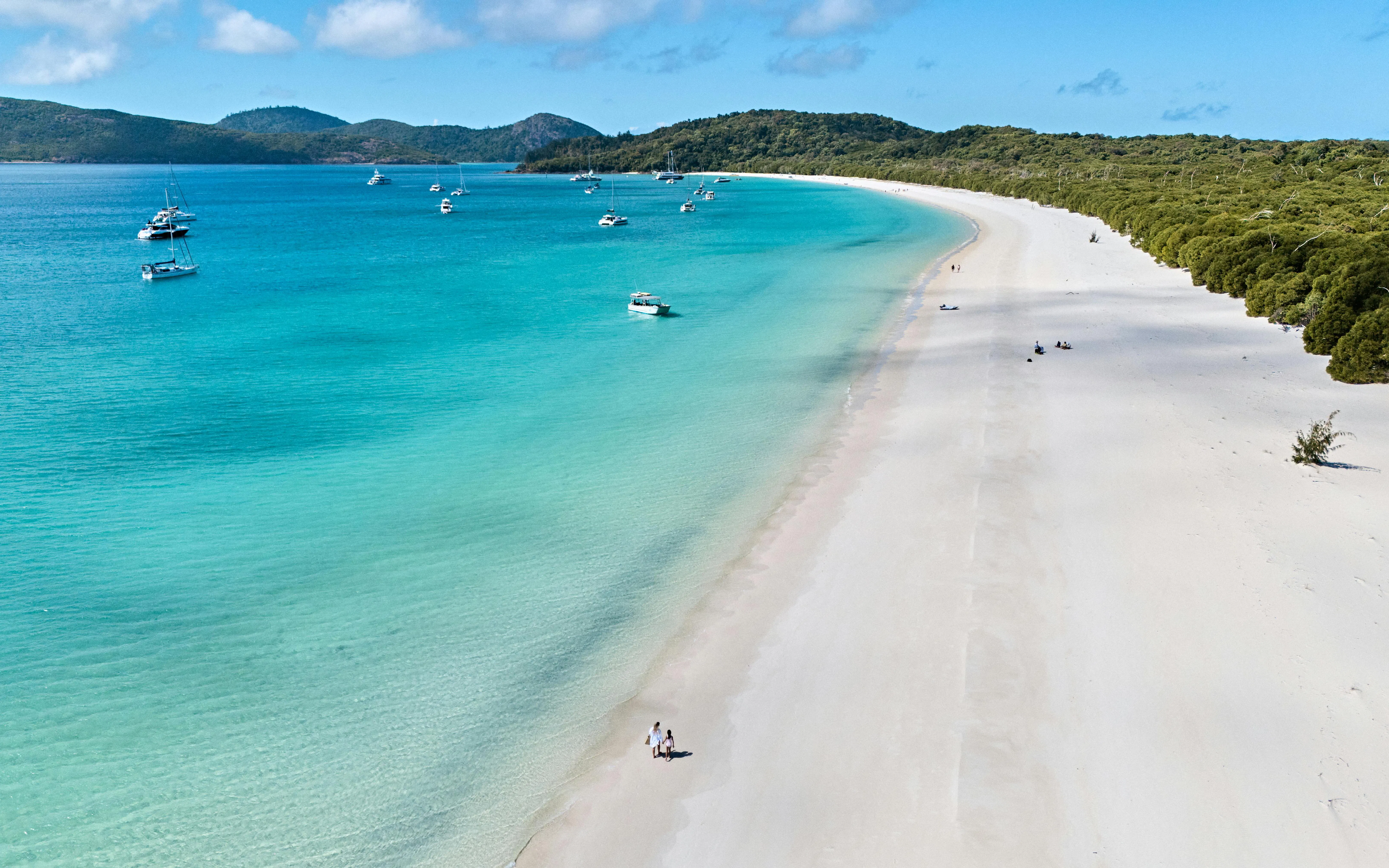 Whitehaven Beach shoreline with boats in turquoise water, Whitsundays Island.