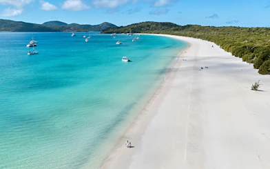 Whitehaven Beach shoreline with boats in turquoise water, Whitsundays Island.