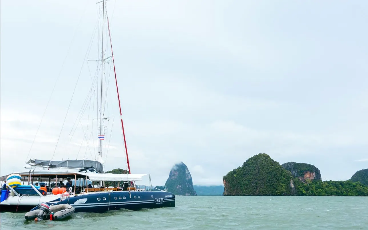 Catamaran boat Ombre Yacht sailing near limestone islands in Phuket, Thailand.