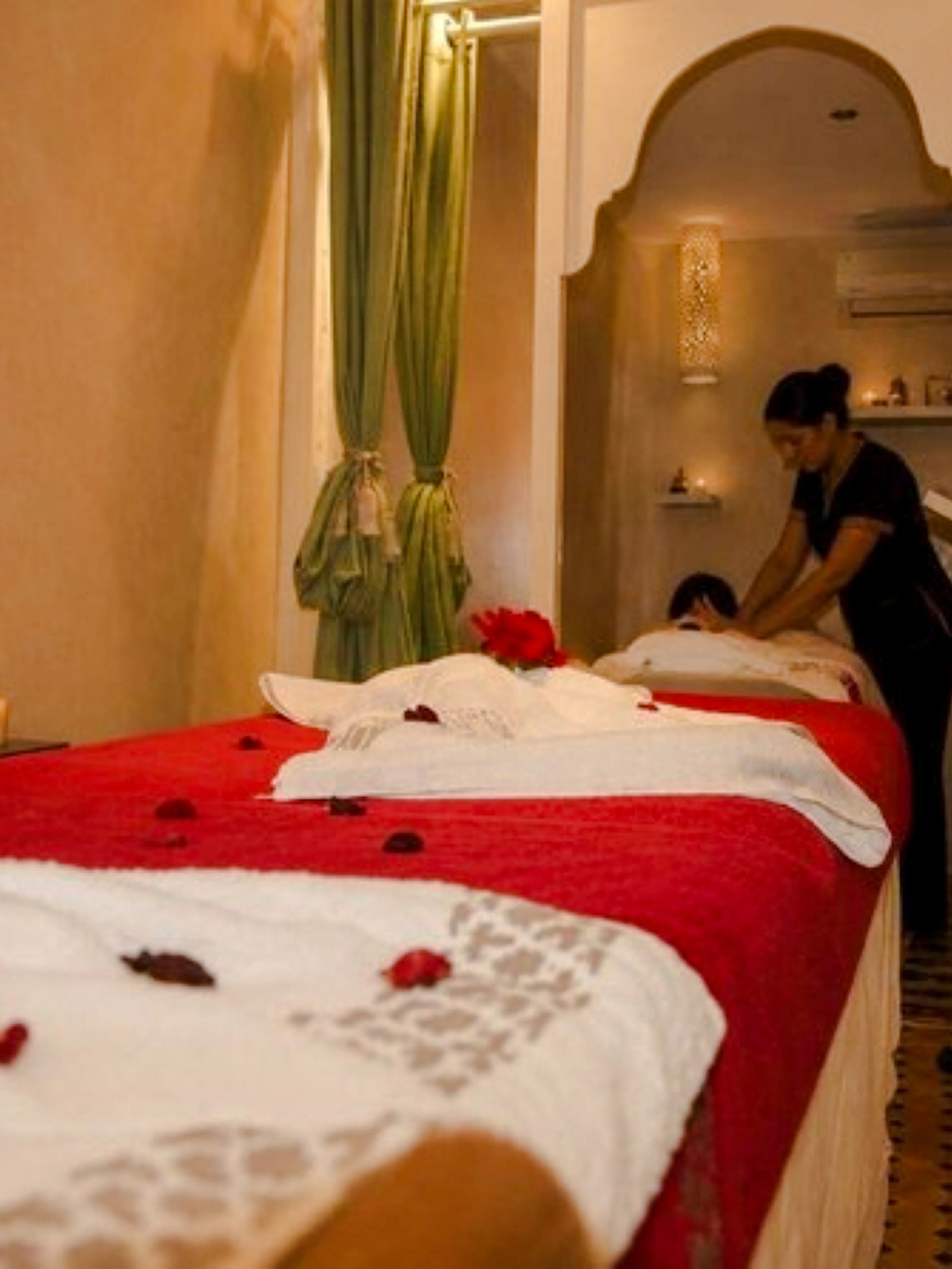 Massage therapist performing treatment in a Marrakech spa room with traditional decor.