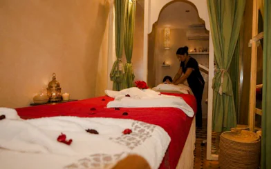 Massage therapist performing treatment in a Marrakech spa room with traditional decor.