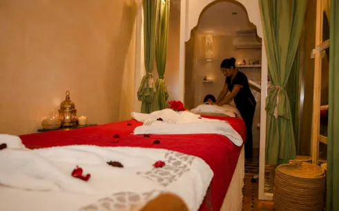 Massage therapist performing treatment in a Marrakech spa room with traditional decor.
