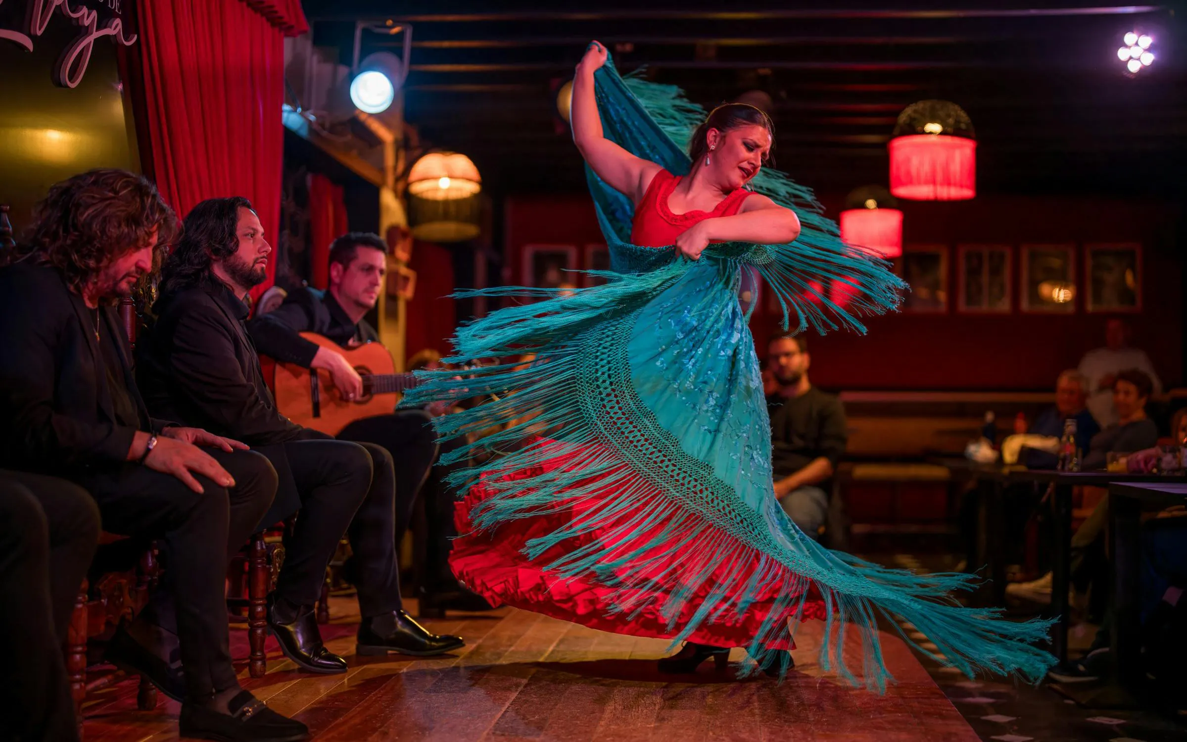 Flamenco dancer performing at Tablao Jardines de Zoraya with musicians in the background.