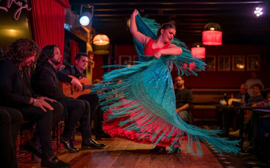 Flamenco dancer performing at Tablao Jardines de Zoraya with musicians in the background.