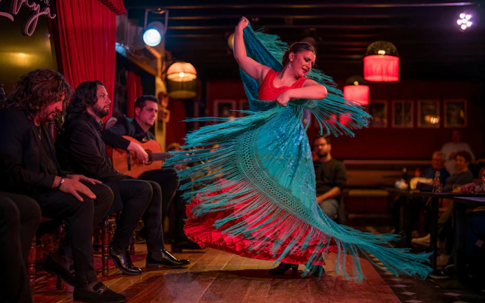 Flamenco dancer performing at Tablao Jardines de Zoraya with musicians in the background.
