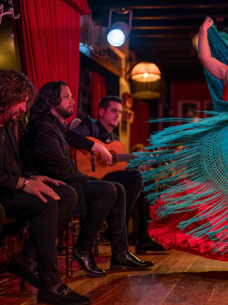 Flamenco dancer performing at Tablao Jardines de Zoraya with musicians in the background.