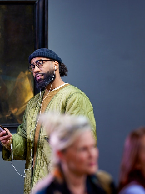 Visitors viewing Rembrandt's "Self-portrait as the Apostle Paul" at a museum exhibit.