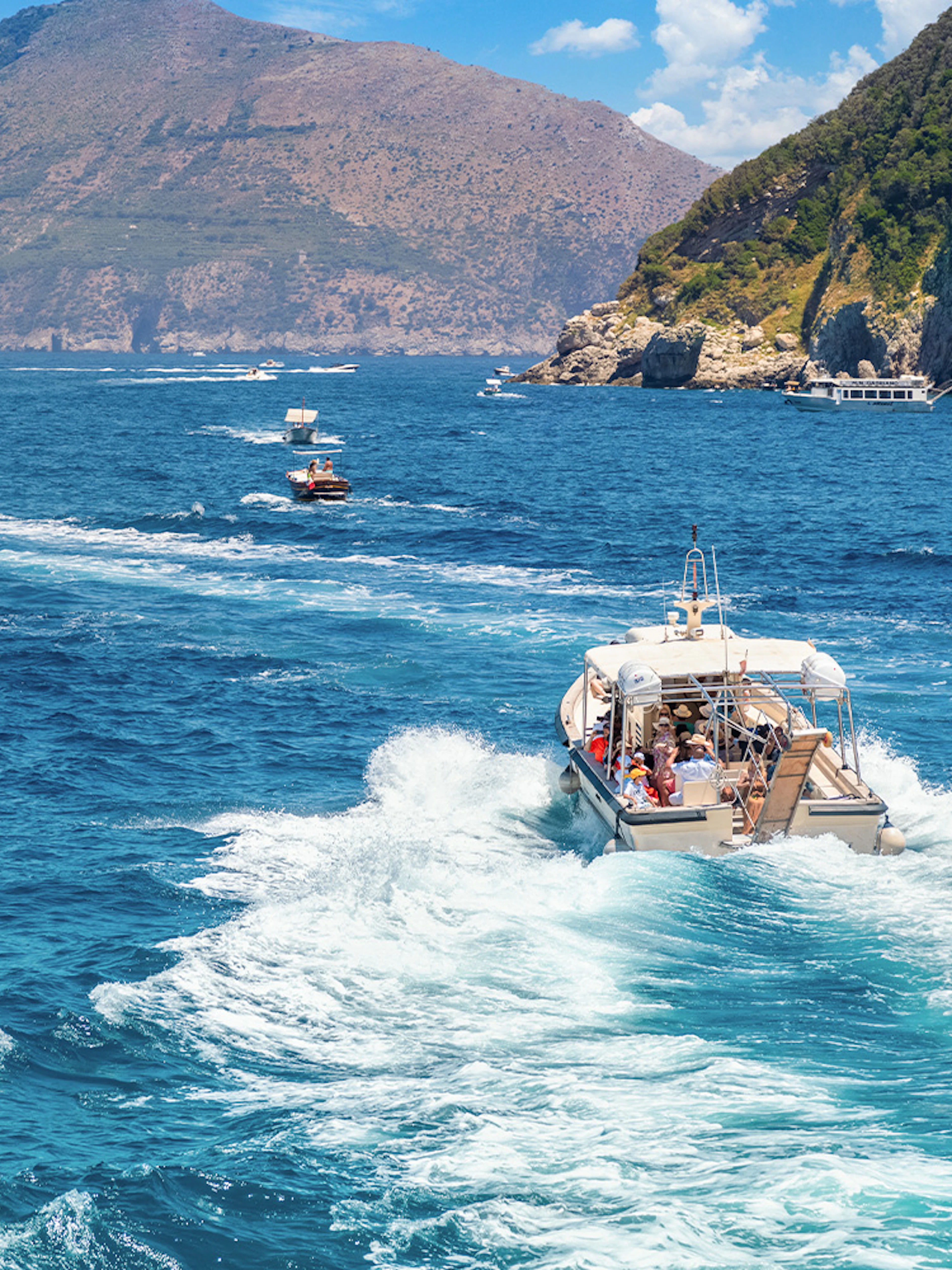 Boat cruising near rocky coastline on Capri tour.
