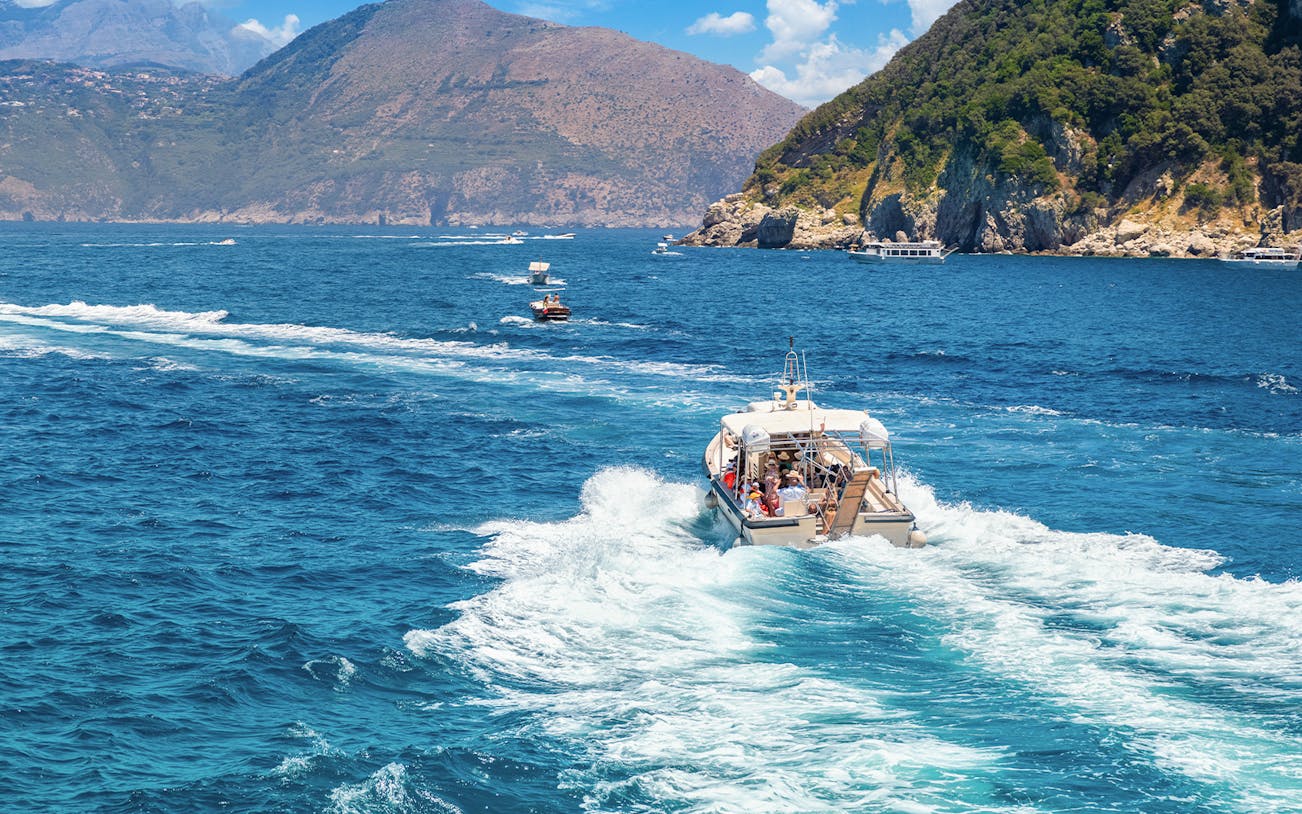 Boat cruising near rocky coastline on Capri tour.